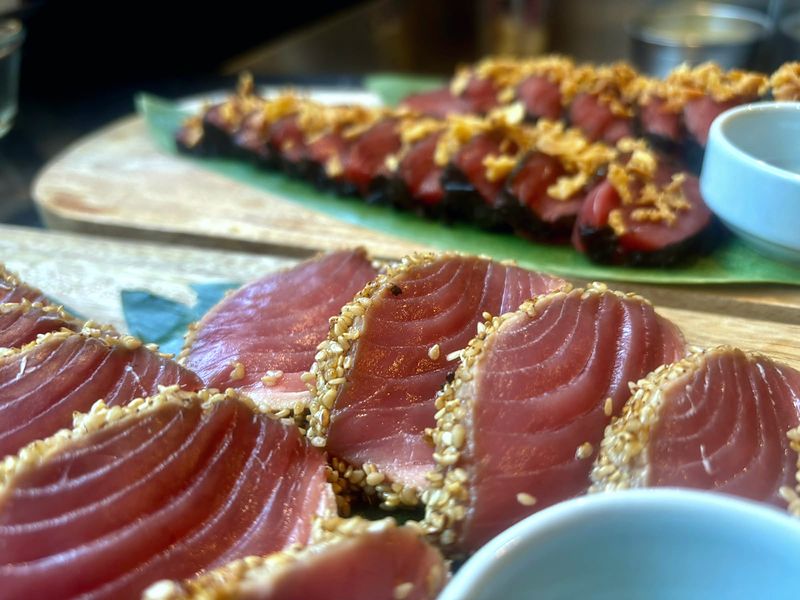 Sesame-crusted tuna tataki, sliced on a wooden board