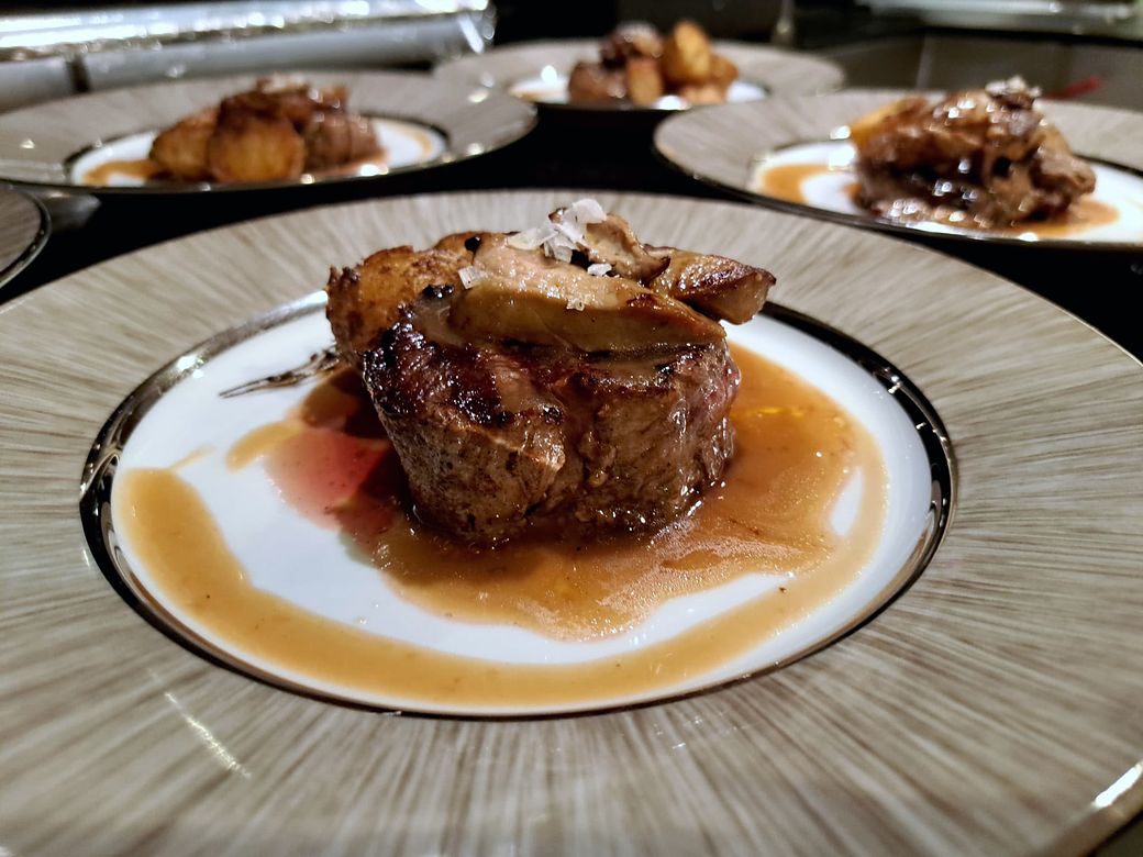Medallion of meat in its jus, topped with roast fruit, during service
