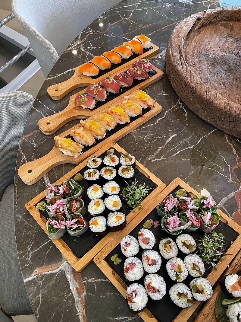 Sushi spread: salmon, tuna and prawn nigiri on wooden boards, with maki and fresh rolls on slate