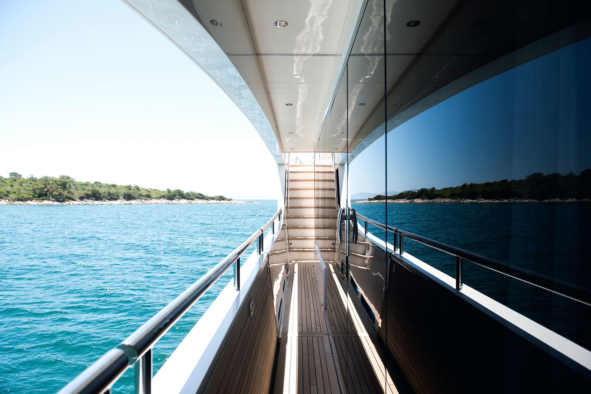 Side deck of a superyacht at anchor, teak walkway and turquoise water