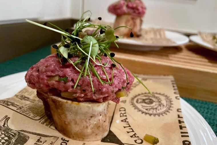 Beef tartare on bone marrow topped with caviar and fresh sprouts